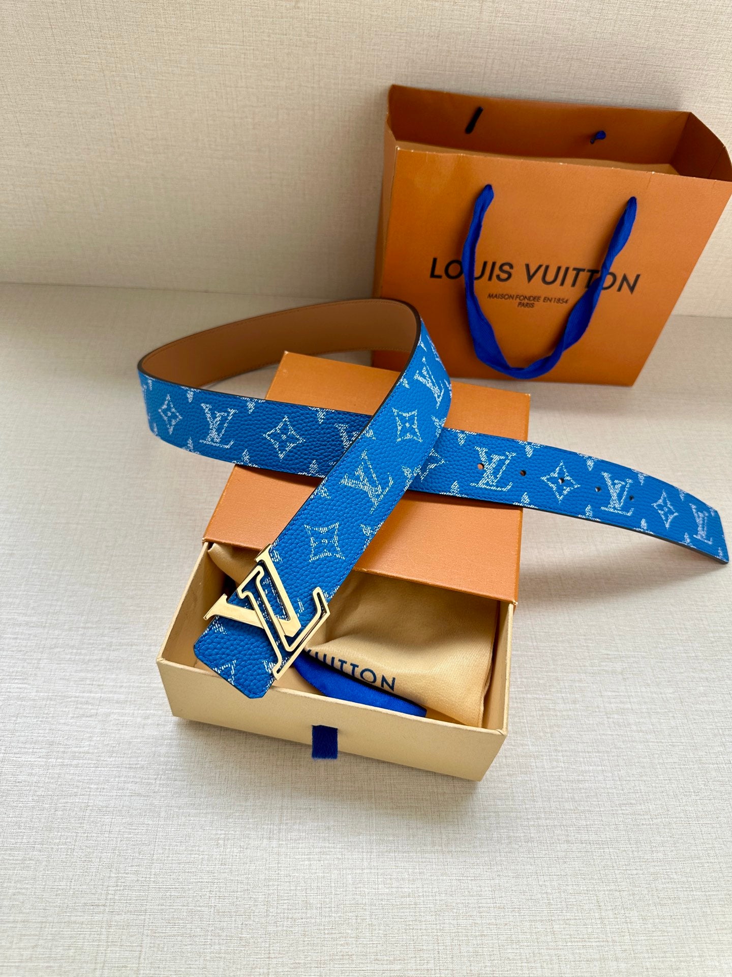 Blue Louis Vuitton belt with monogram weave, LV buckle, and tan leather side