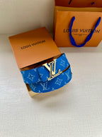 Blue monogram Louis Vuitton belt with silver-tone LV buckle, laid on box