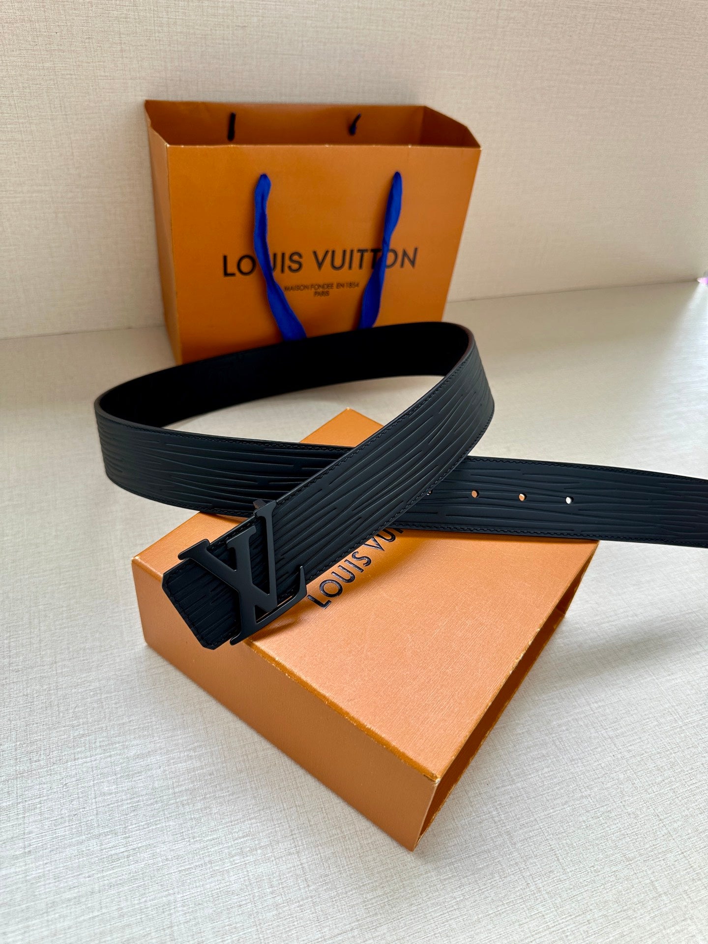 Louis Vuitton belt with dark textured strap and LV logo buckle