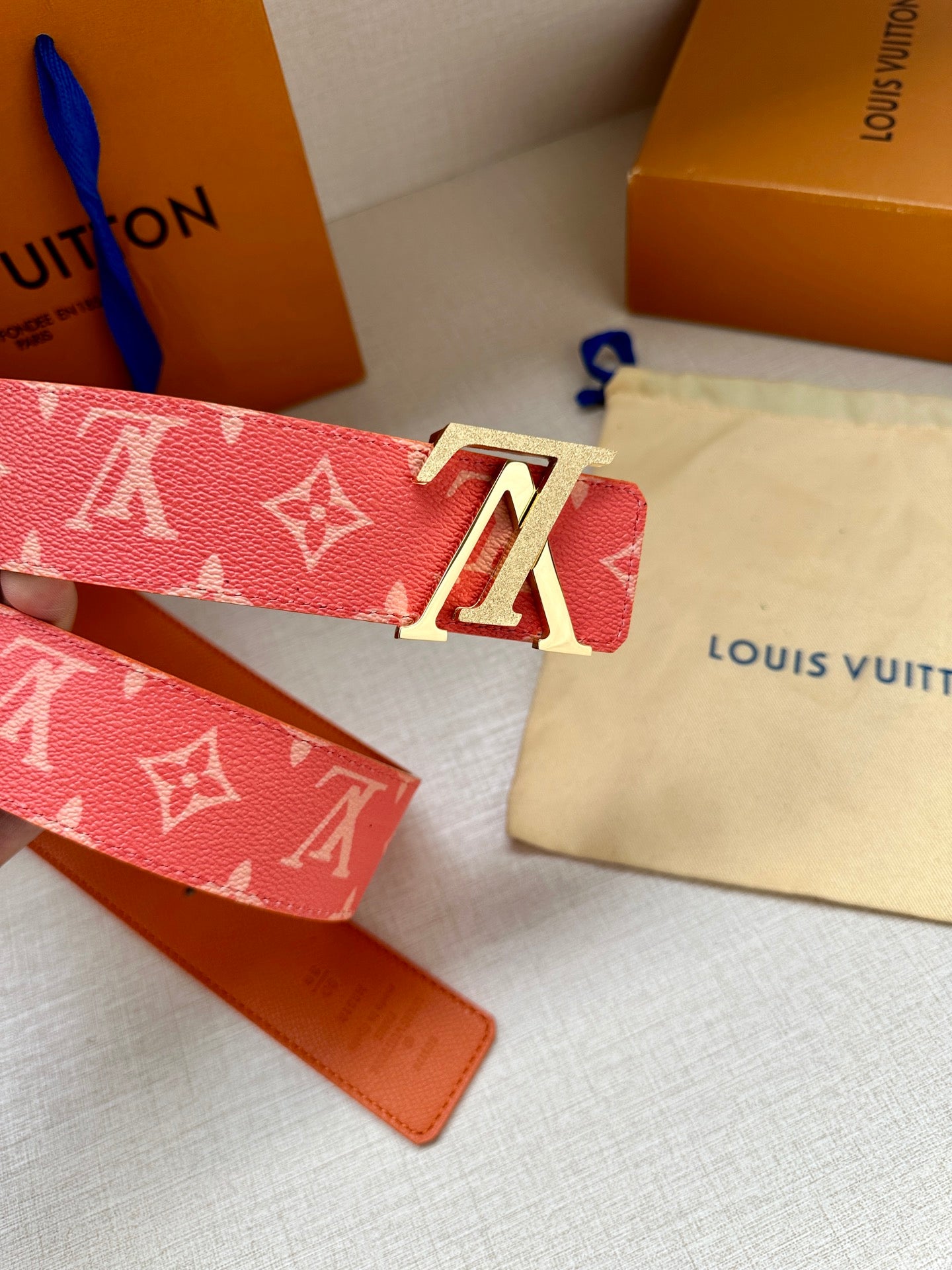 Louis Vuitton belt with red monogram canvas and gold-tone LV buckle, showing strap edges