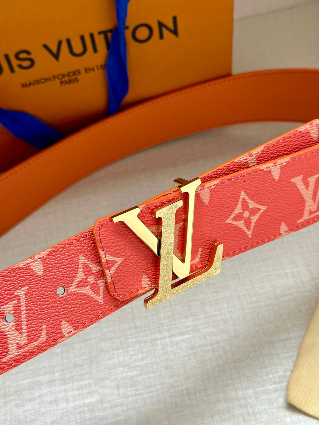 Louis Vuitton belt close-up: red monogram strap with gold-tone LV buckle