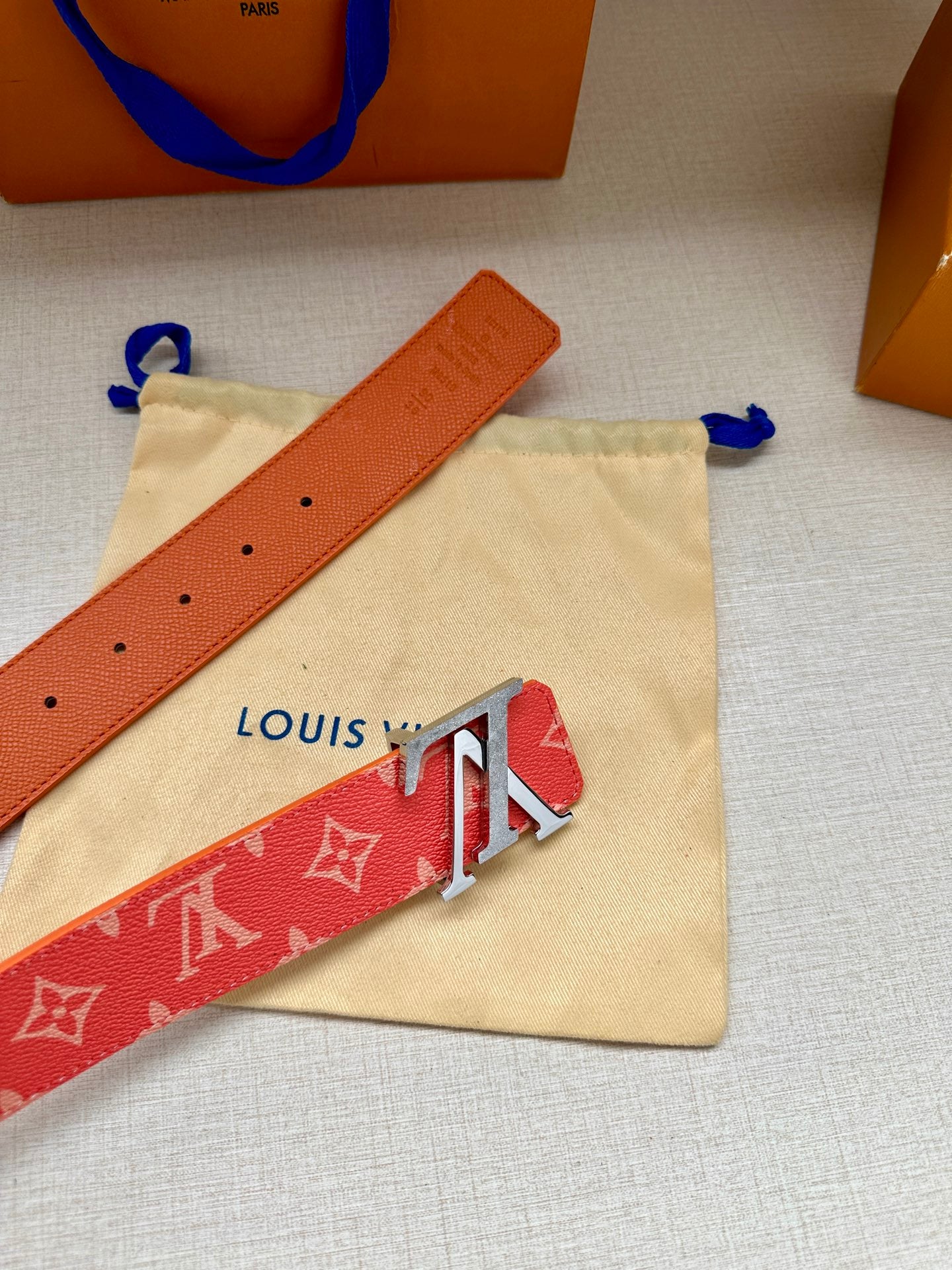 Louis Vuitton belt close-up: red monogram strap with gold-tone LV buckle and hole details