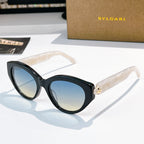 Bvlgari cat-eye sunglasses, dark frames, blue-tinted lenses, gold emblem bridge