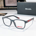 Prada glasses with light gray frames and clear lenses, red logo temple detail