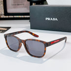 Prada glasses with tortoiseshell frames and dark tinted lenses, red logo temple detail