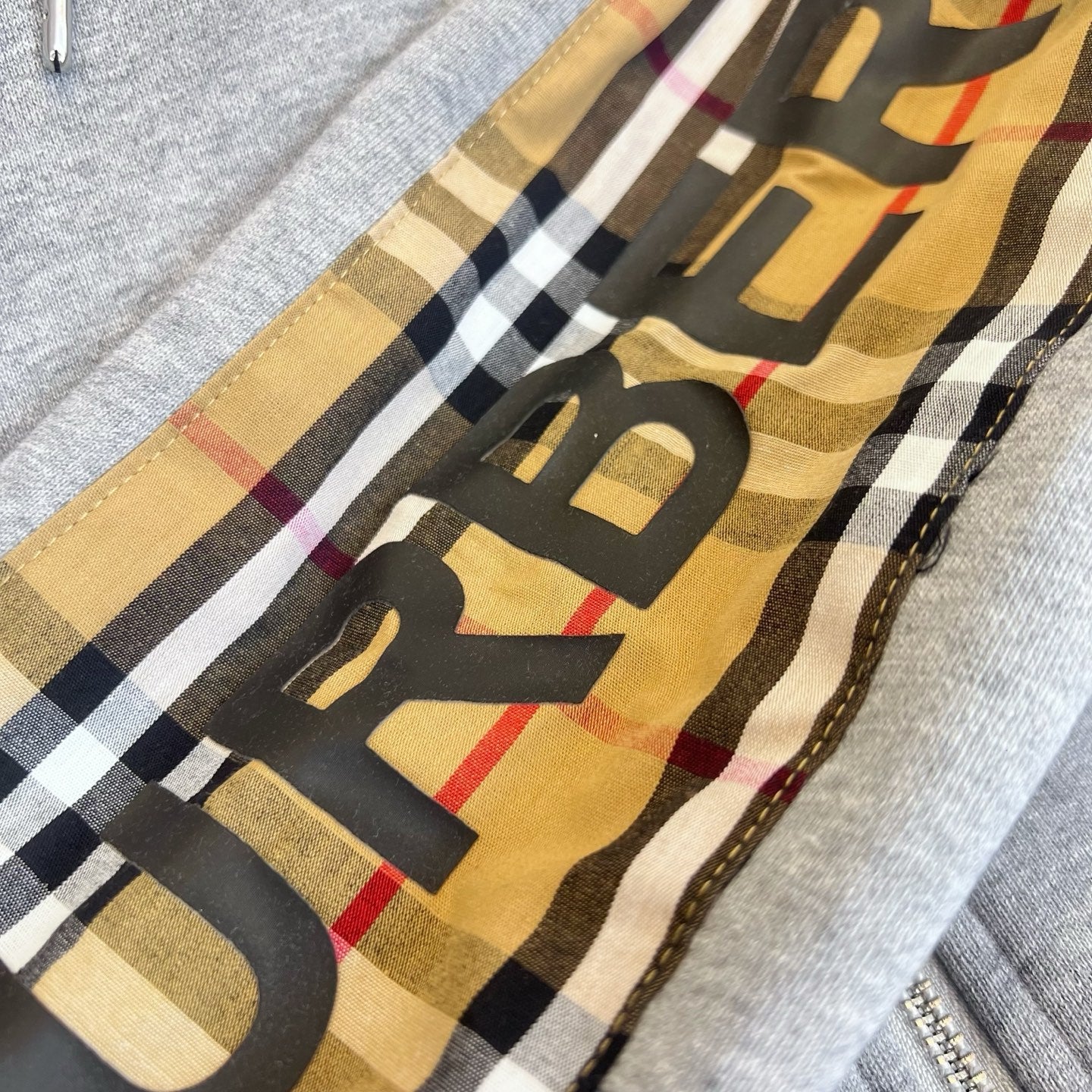Light gray zip-up hoodie with multicolor check panel and stitched hood trim