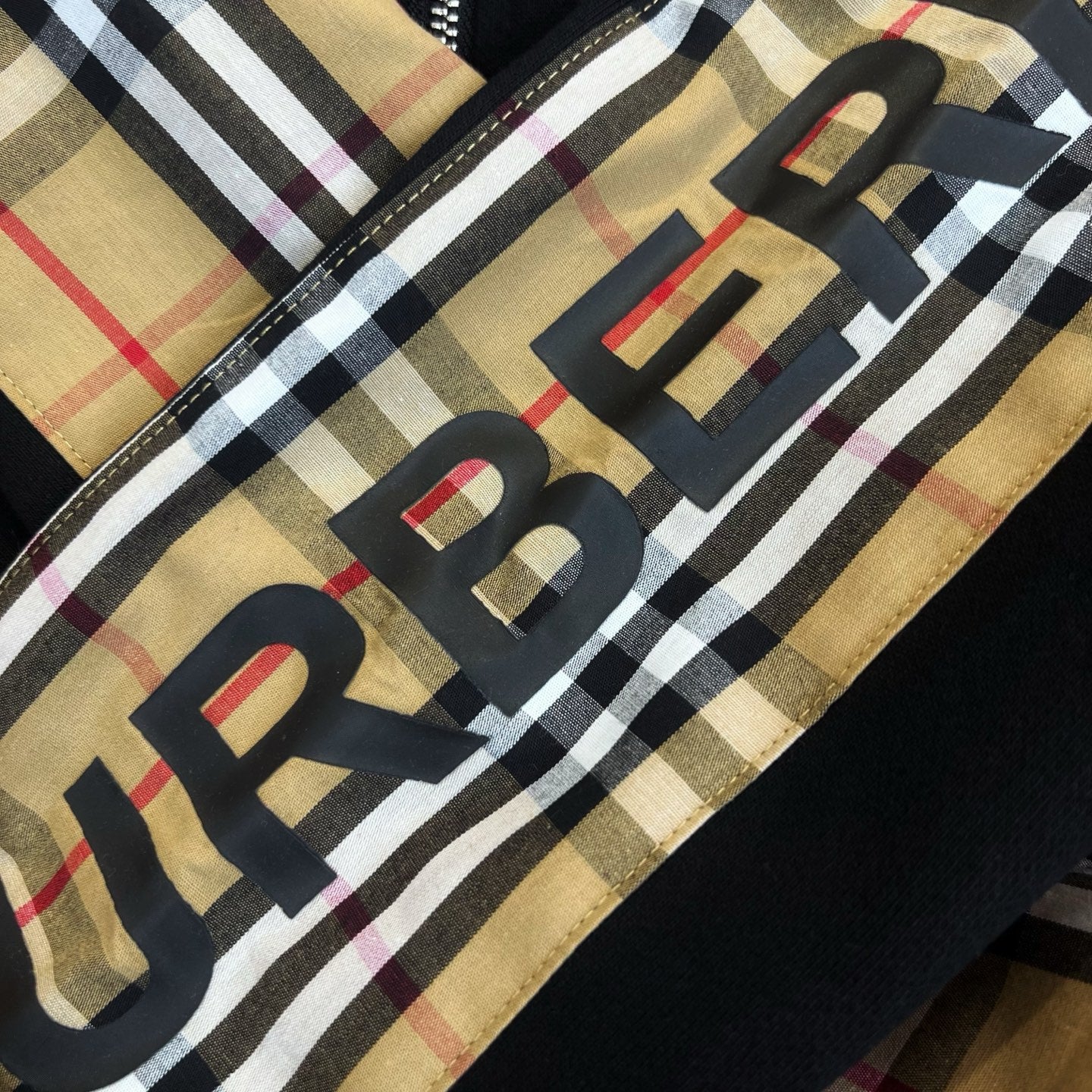 Plaid hood panel fabric with large black letters and red accents