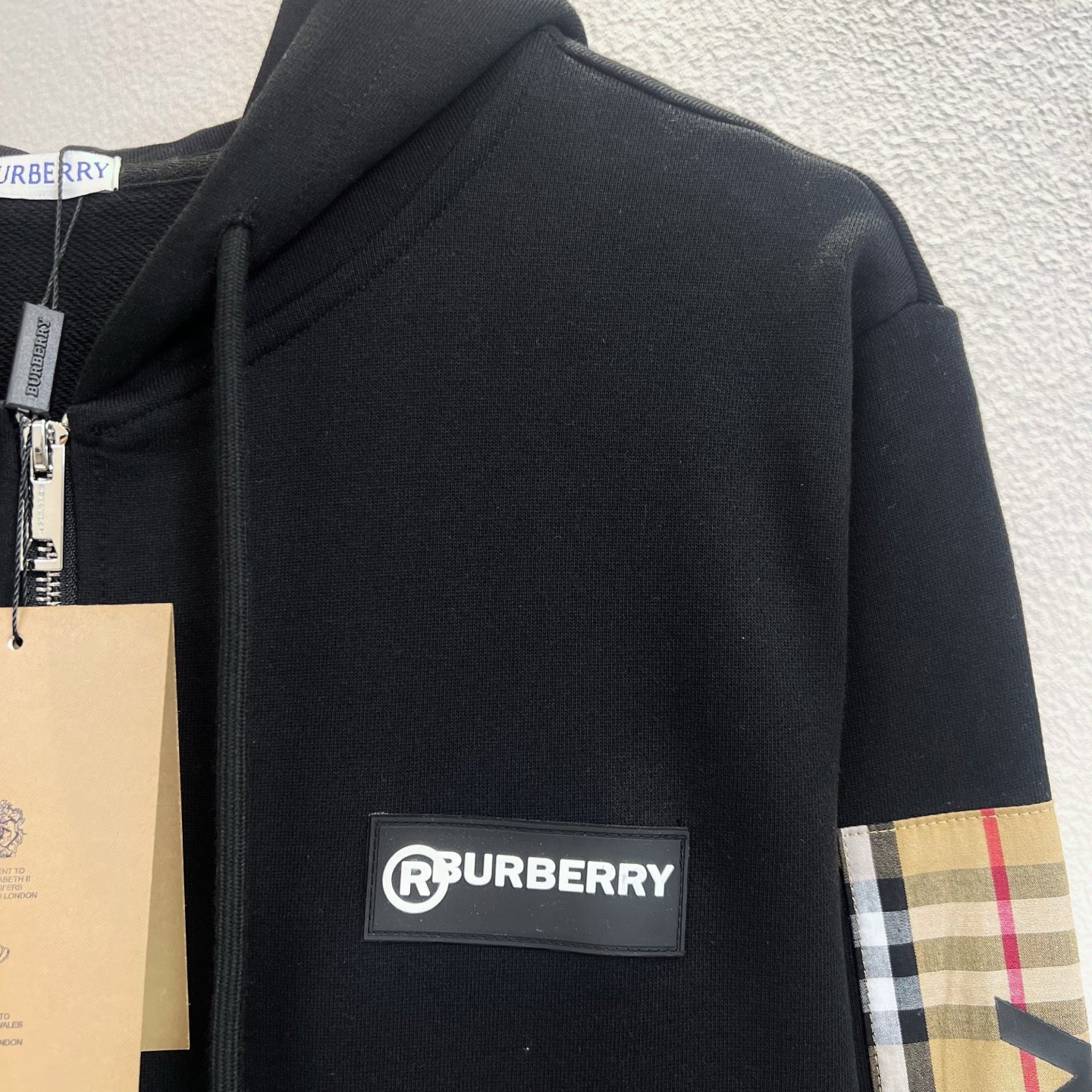Black hooded zip jacket with front Burberry logo patch and plaid sleeve trim