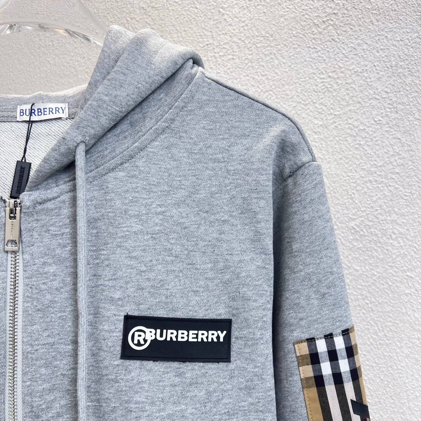 Gray zip hoodie with drawstring hood, Burberry logo patch and plaid sleeve panel.
