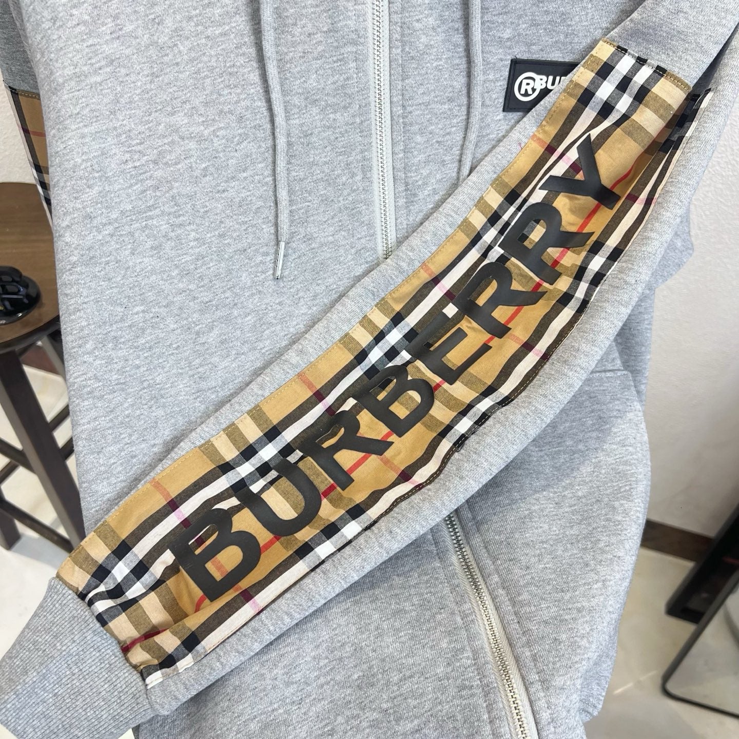 Gray hoodie sleeve panel with plaid trim and BURBERRY logo print.