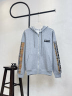 Light gray zip-up hoodie with hood, front zipper and plaid sleeve accents.