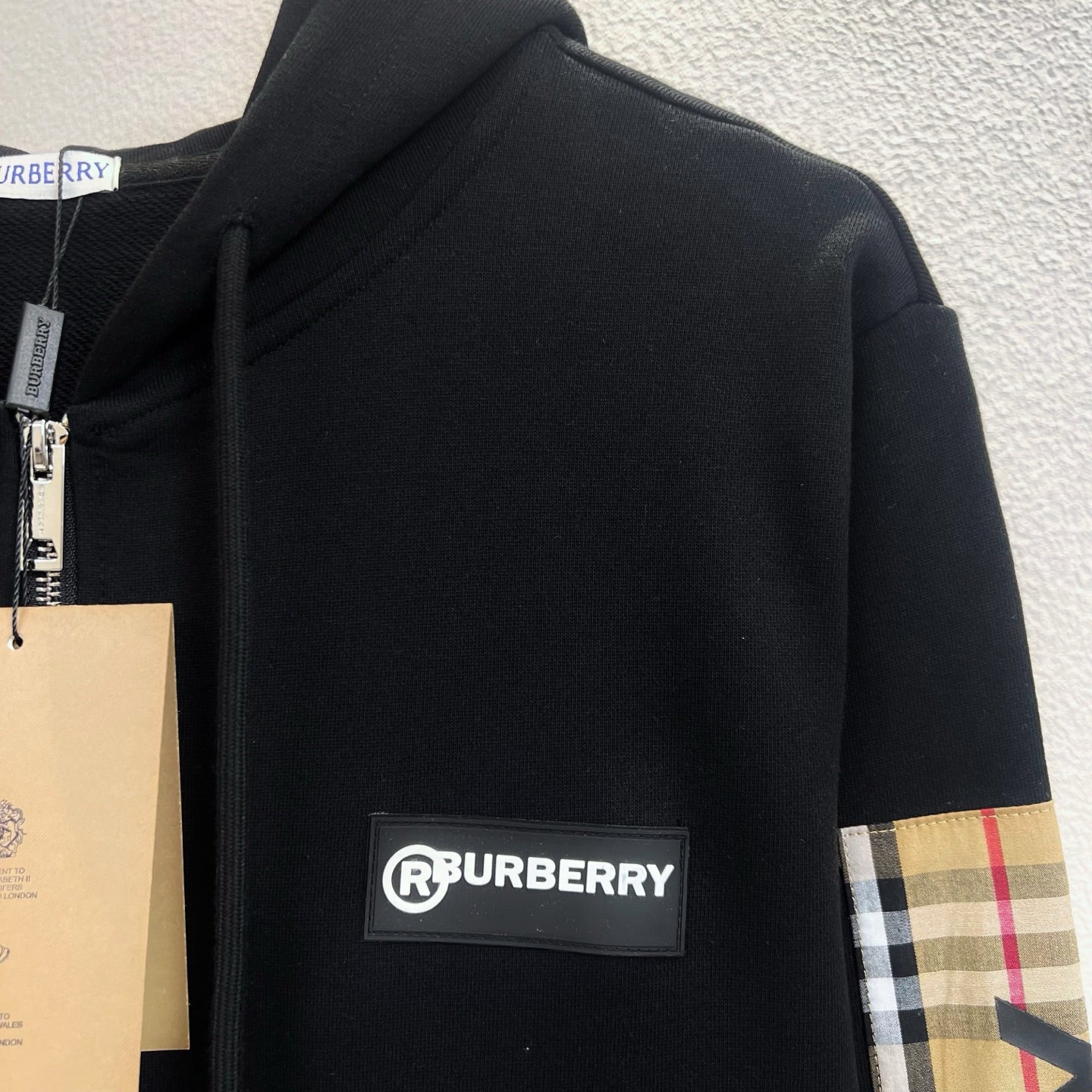 Black zip-up hoodie with Burberry logo patch and plaid panel on sleeve
