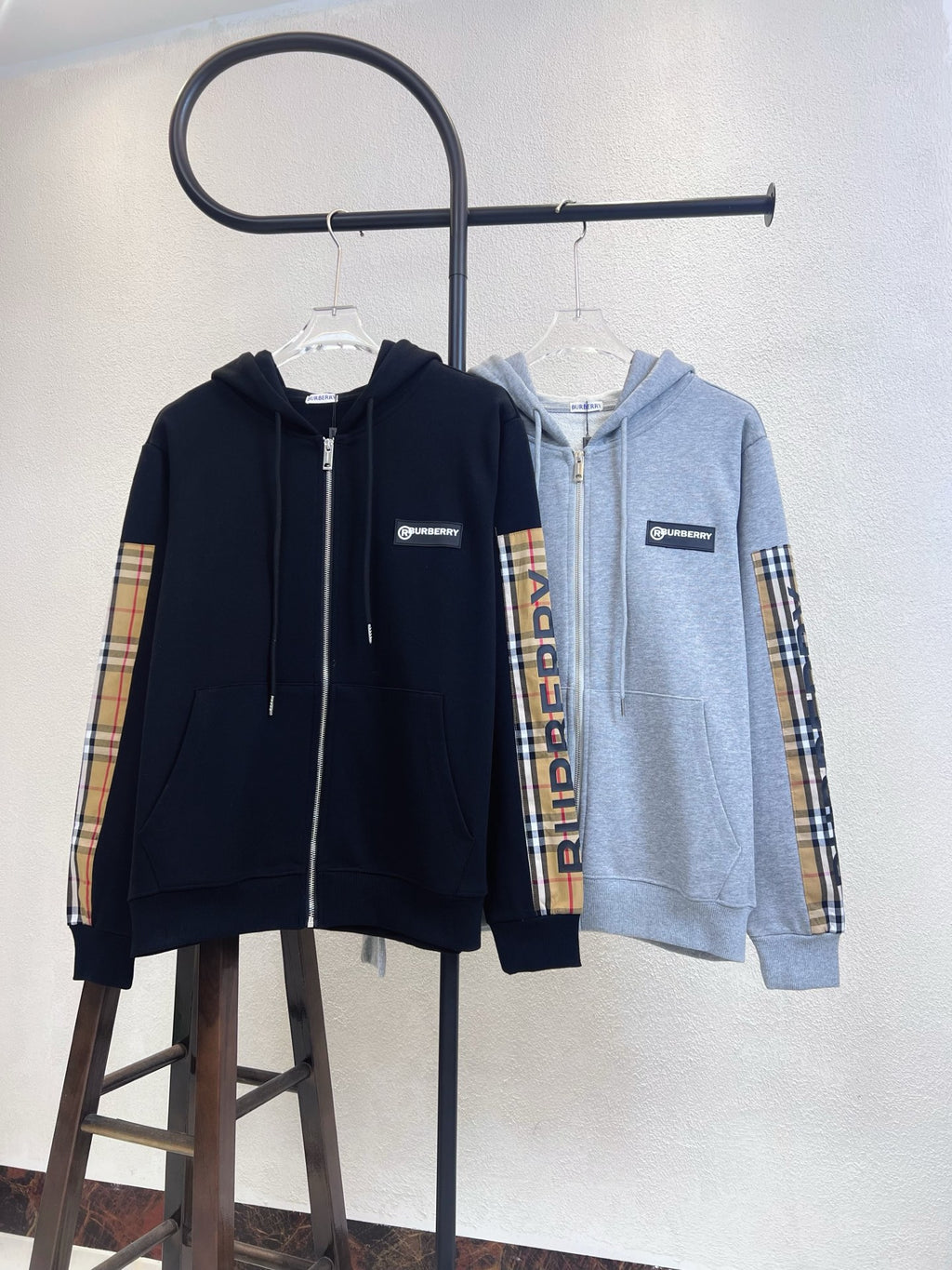 Zip-up hoodies on hangers: navy and light gray with plaid sleeve panels.