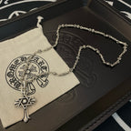 Silver-tone chain necklace with cross star pendant hanging beside a circular charm