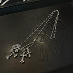 Silver-tone cross pendant necklace with chain links and small charm accents