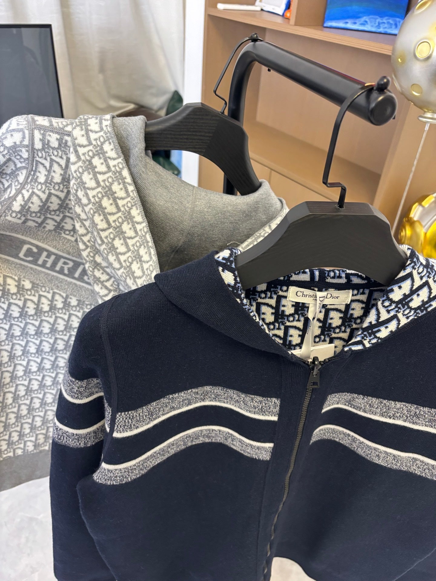 Dior hooded zip jacket close-up: dark navy body, striped sleeves, patterned hood lining