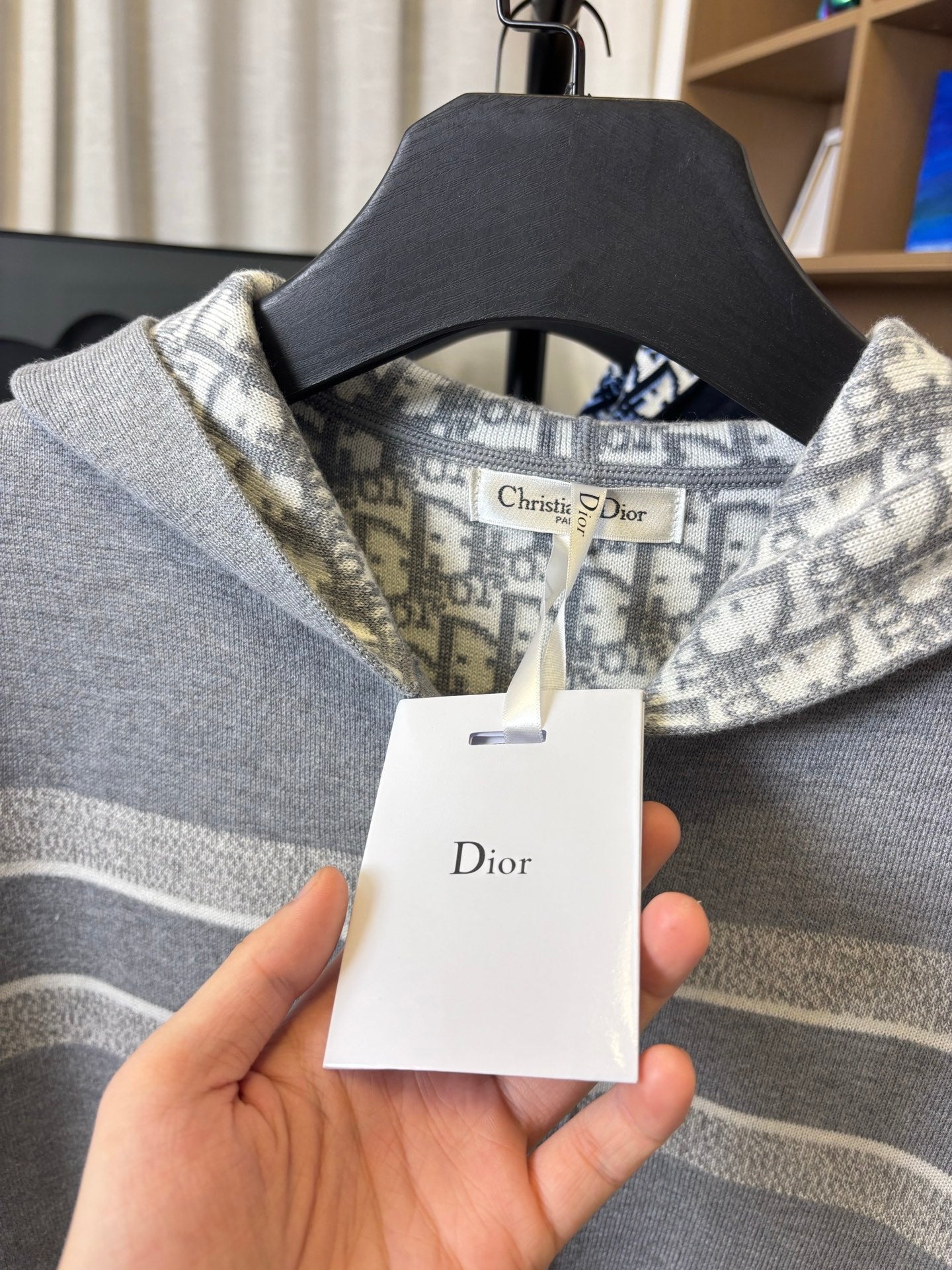 Gray Dior logo hoodie neckline close-up with hanging product tag