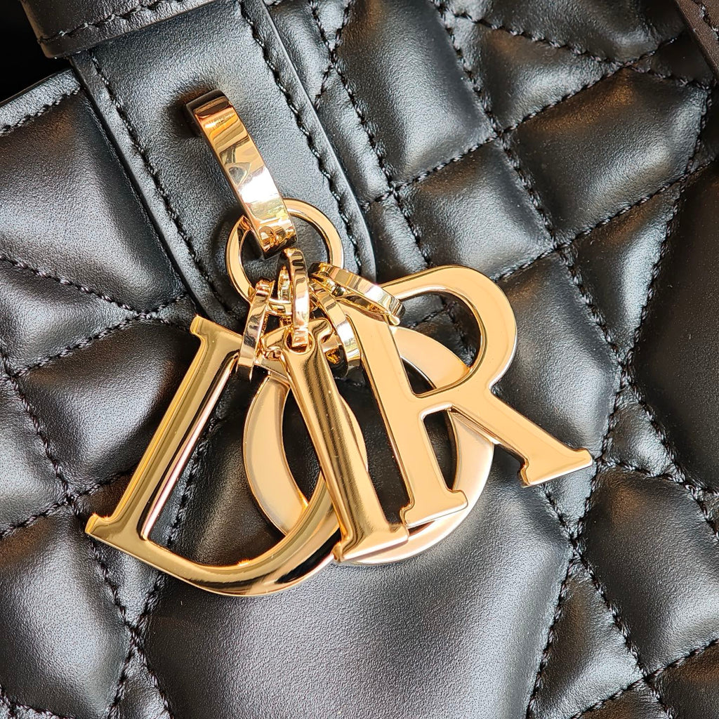 Gold D-R logo charm on quilted dark blue bag, metal hardware