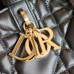 Gold D-R logo charm on quilted dark blue bag, metal hardware