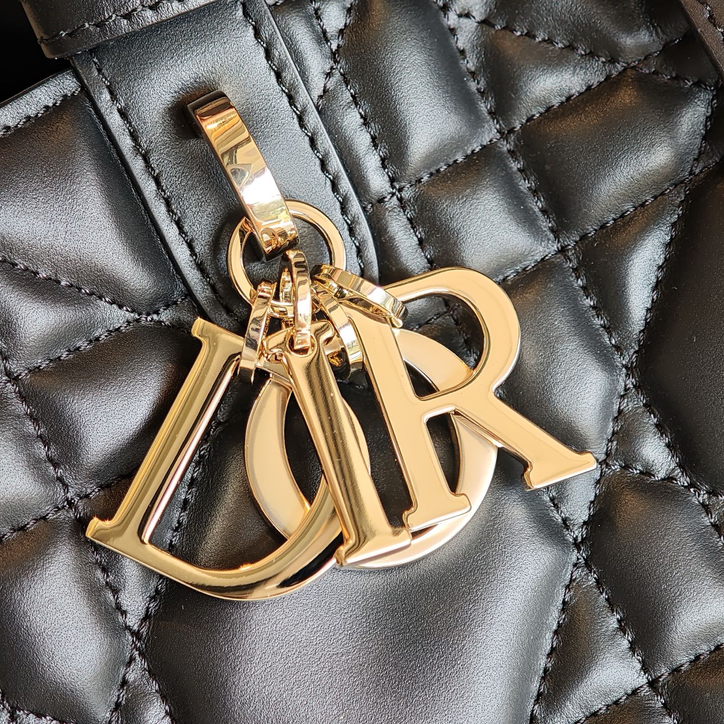 Gold D-R logo charm on quilted dark blue bag, metal hardware
