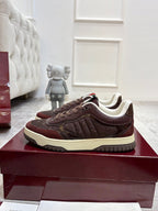 Brown lace-up sneaker with embossed pattern, cream sole, and green-red heel stripe