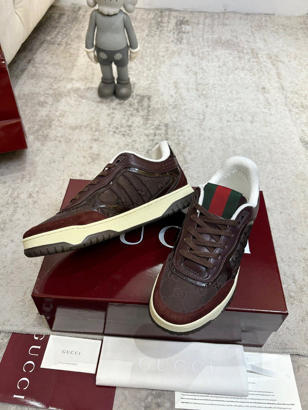Pair of brown lace-up sneakers with cream sole and green-red striped collar