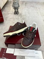 Low-top sneakers close-up, dark brown with green-red collar web and cream sole edge