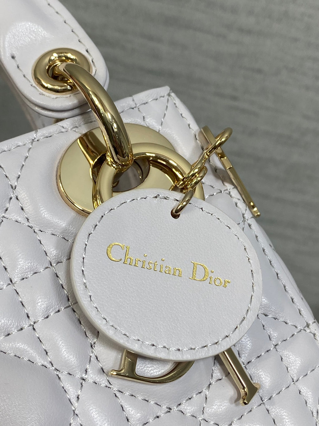 Dior bag charm and clasp close-up with gold hardware and circular logo tag