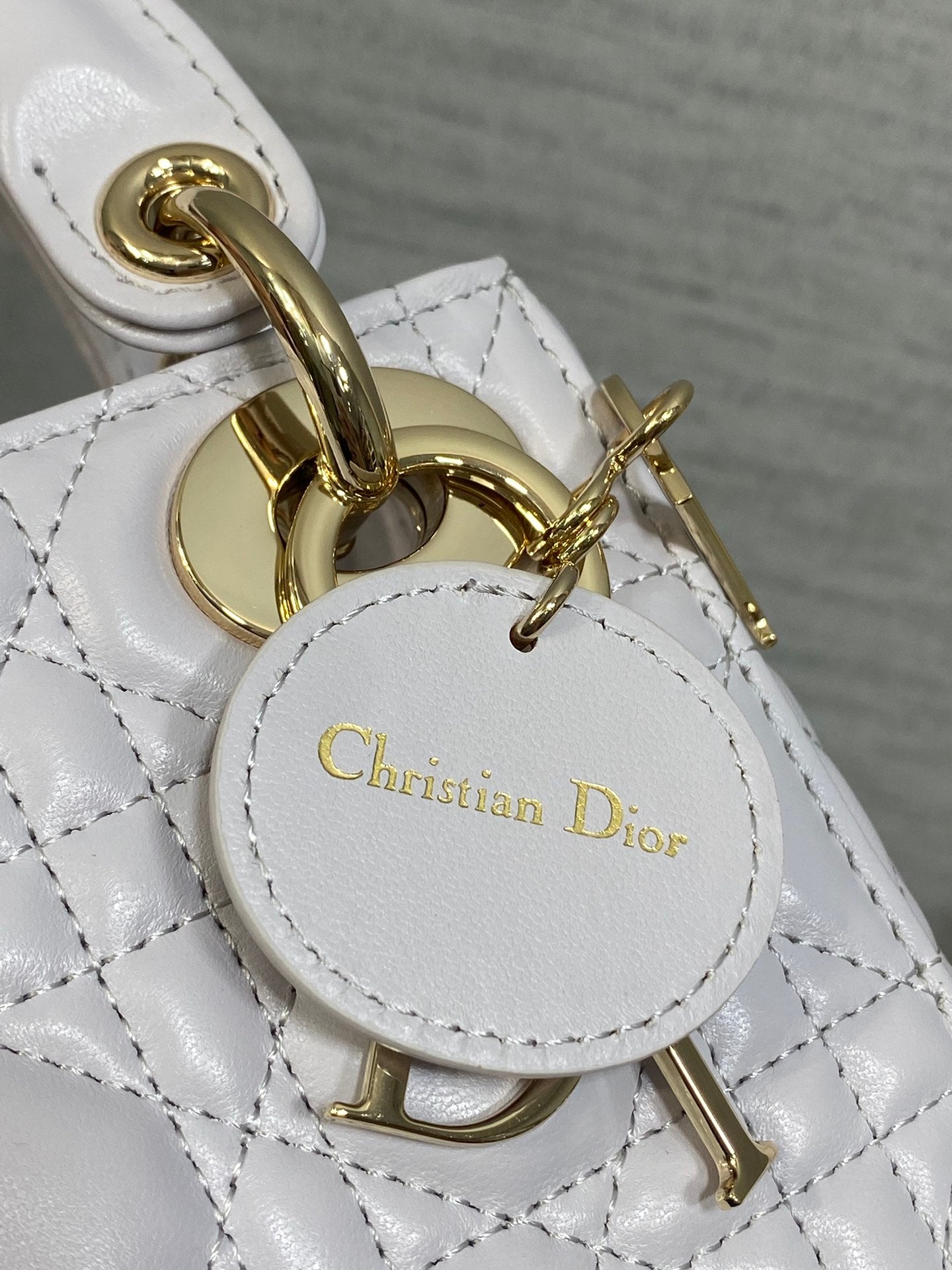Dior bag charm and clasp close-up with gold hardware and circular logo tag