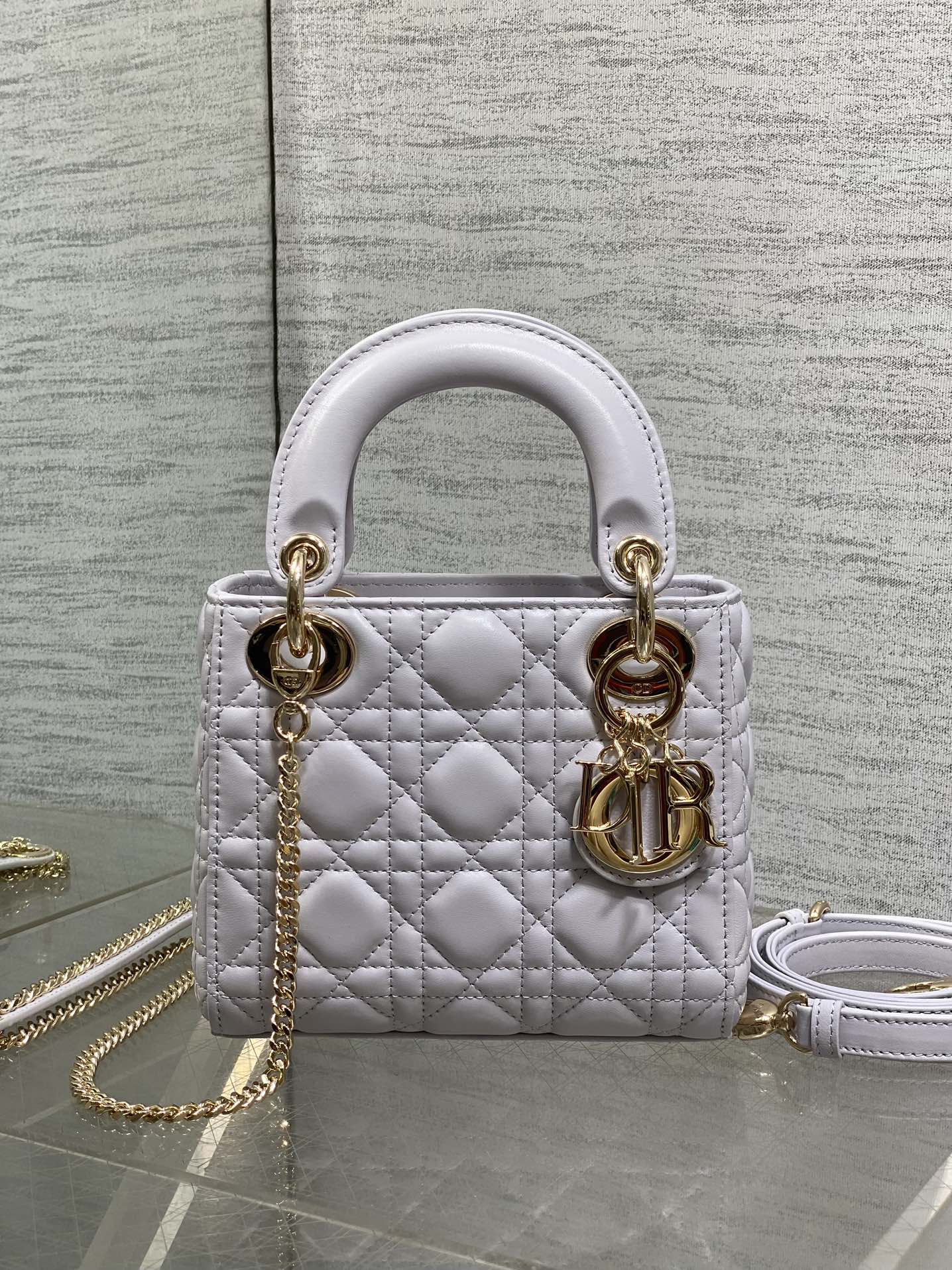Dior quilted mini bag, front view, with top handles, gold rings, and chain strap