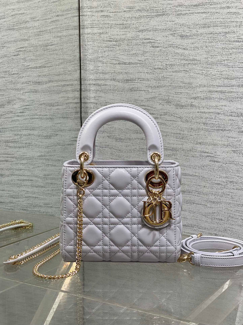 Dior quilted mini bag with top handles, gold hardware, and a detachable chain strap