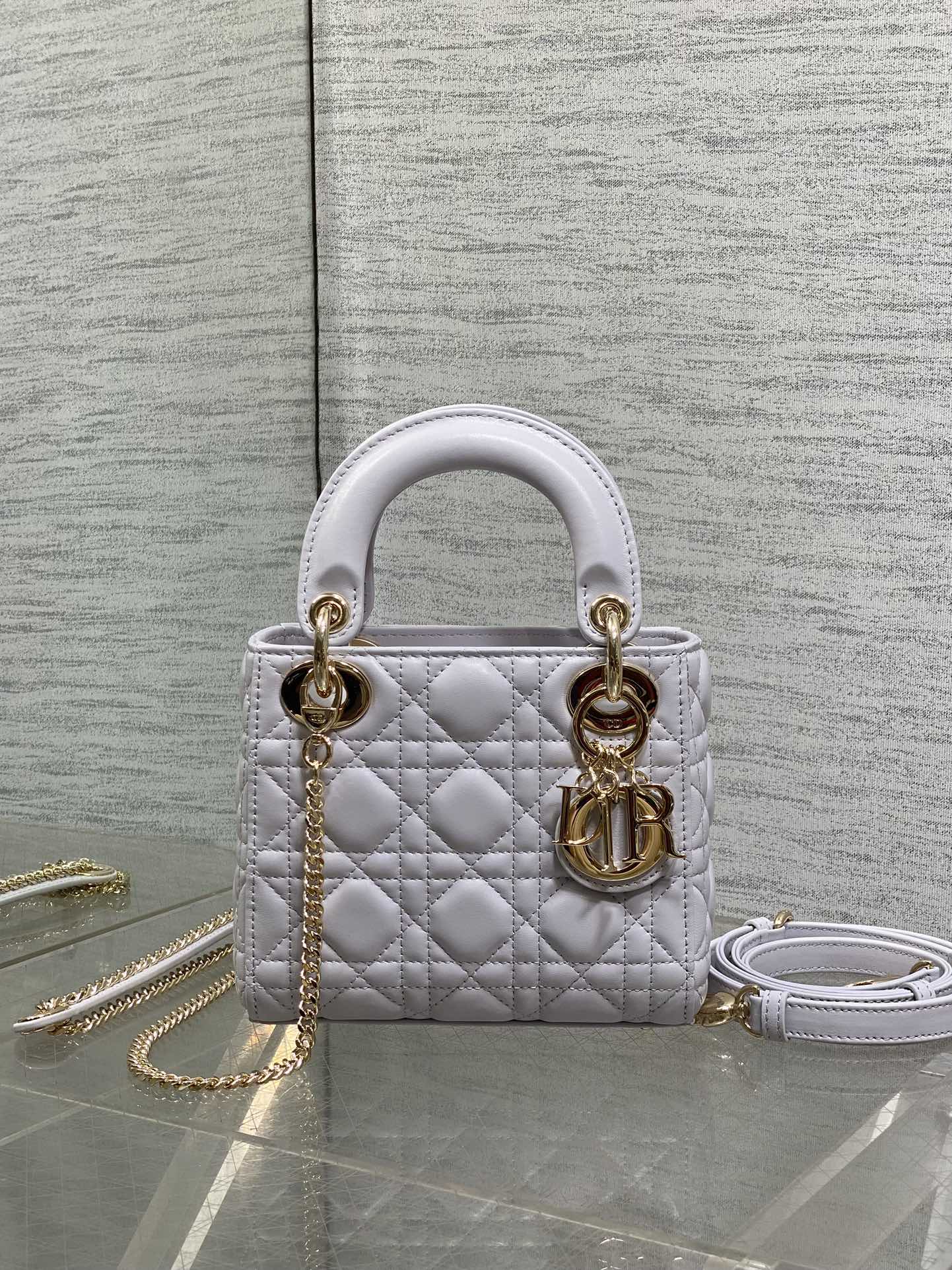 Dior quilted mini bag with top handles, gold hardware, and a detachable chain strap