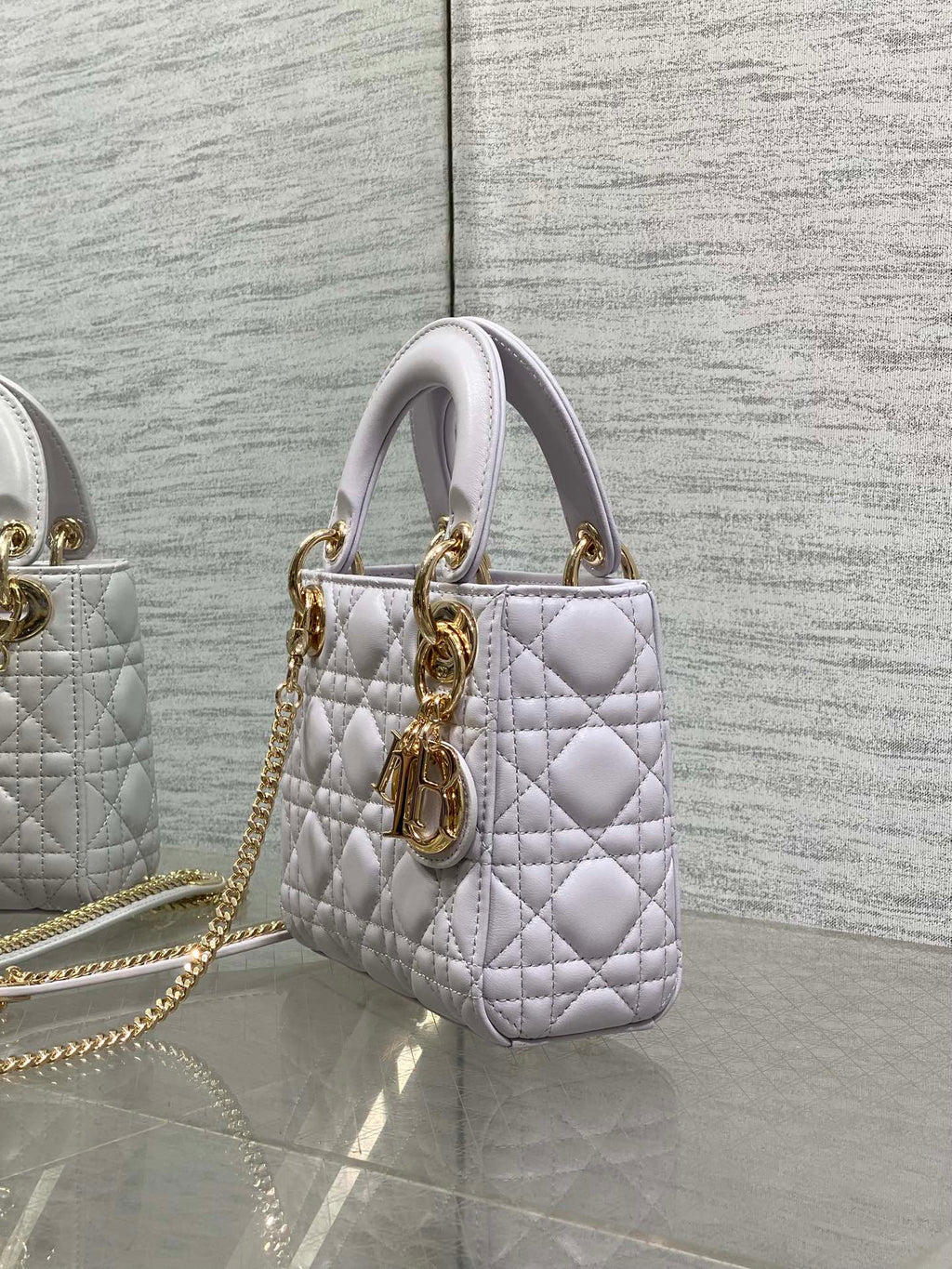 Dior quilted mini bag side view with top handles and gold chain strap hardware