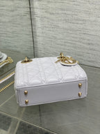 Dior structured mini bag with top handle, gold feet, and logo charm on front