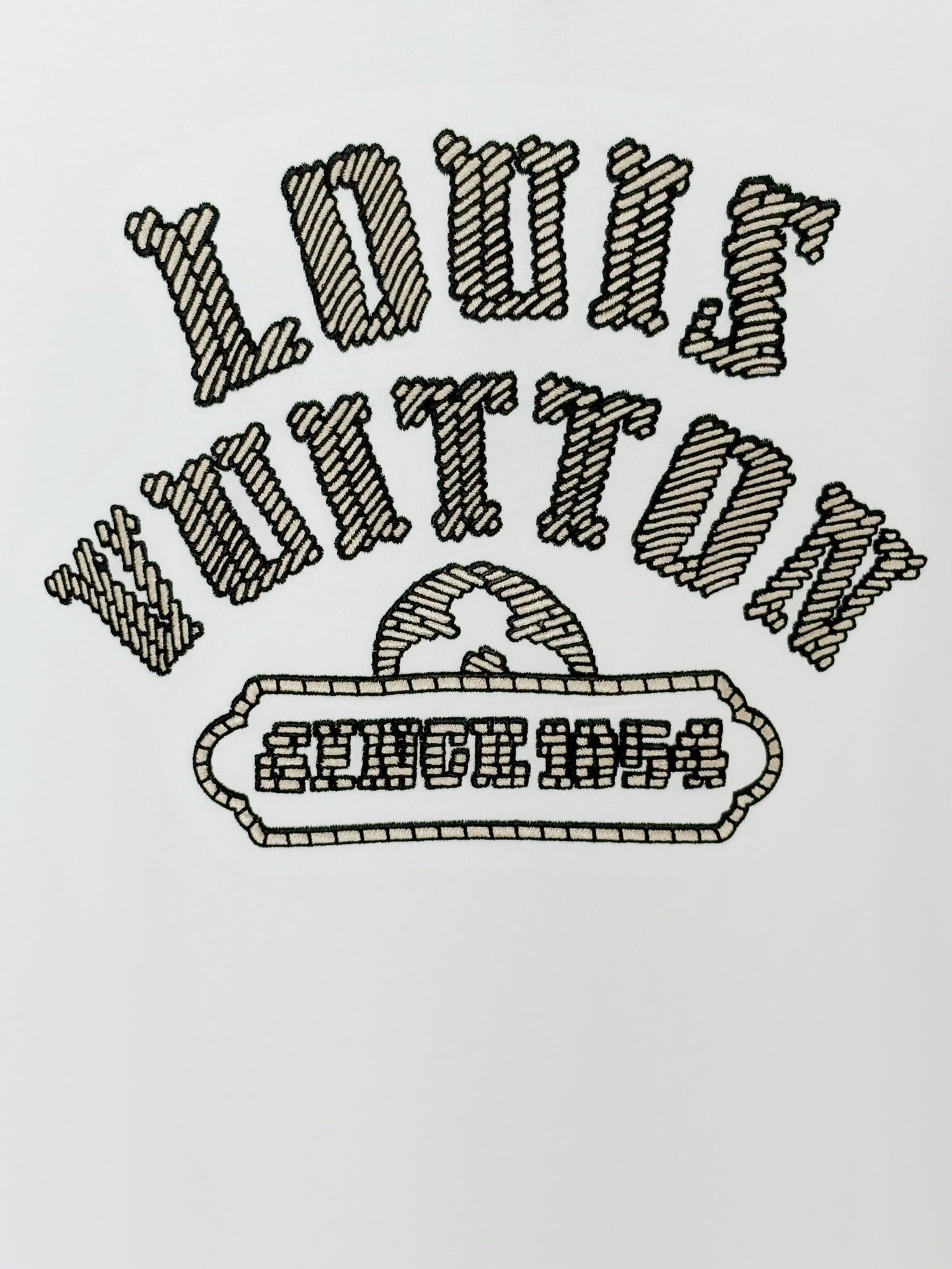 White Louis Vuitton T-shirt close-up of embroidered text and emblem graphic