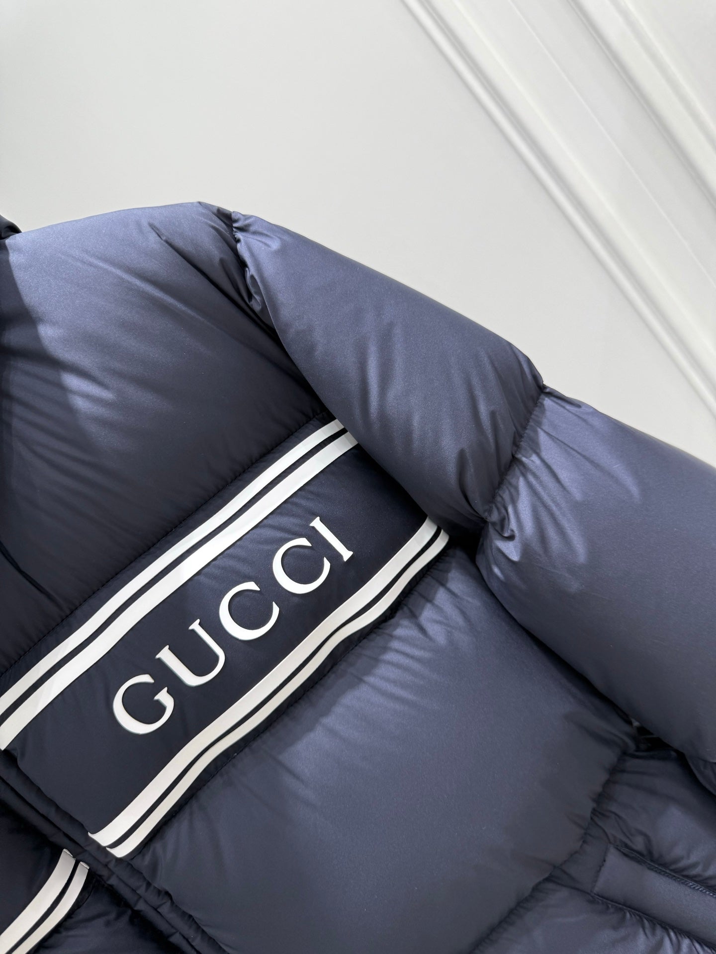 Dark blue puffer jacket with hood and Gucci logo stripe on the chest