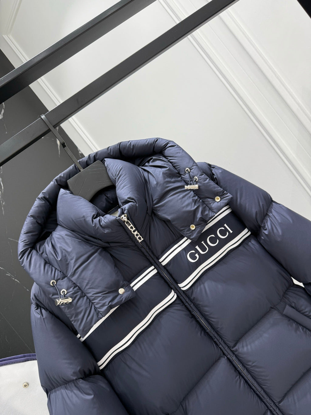 Dark blue hooded puffer jacket with striped Gucci logo band and snap buttons