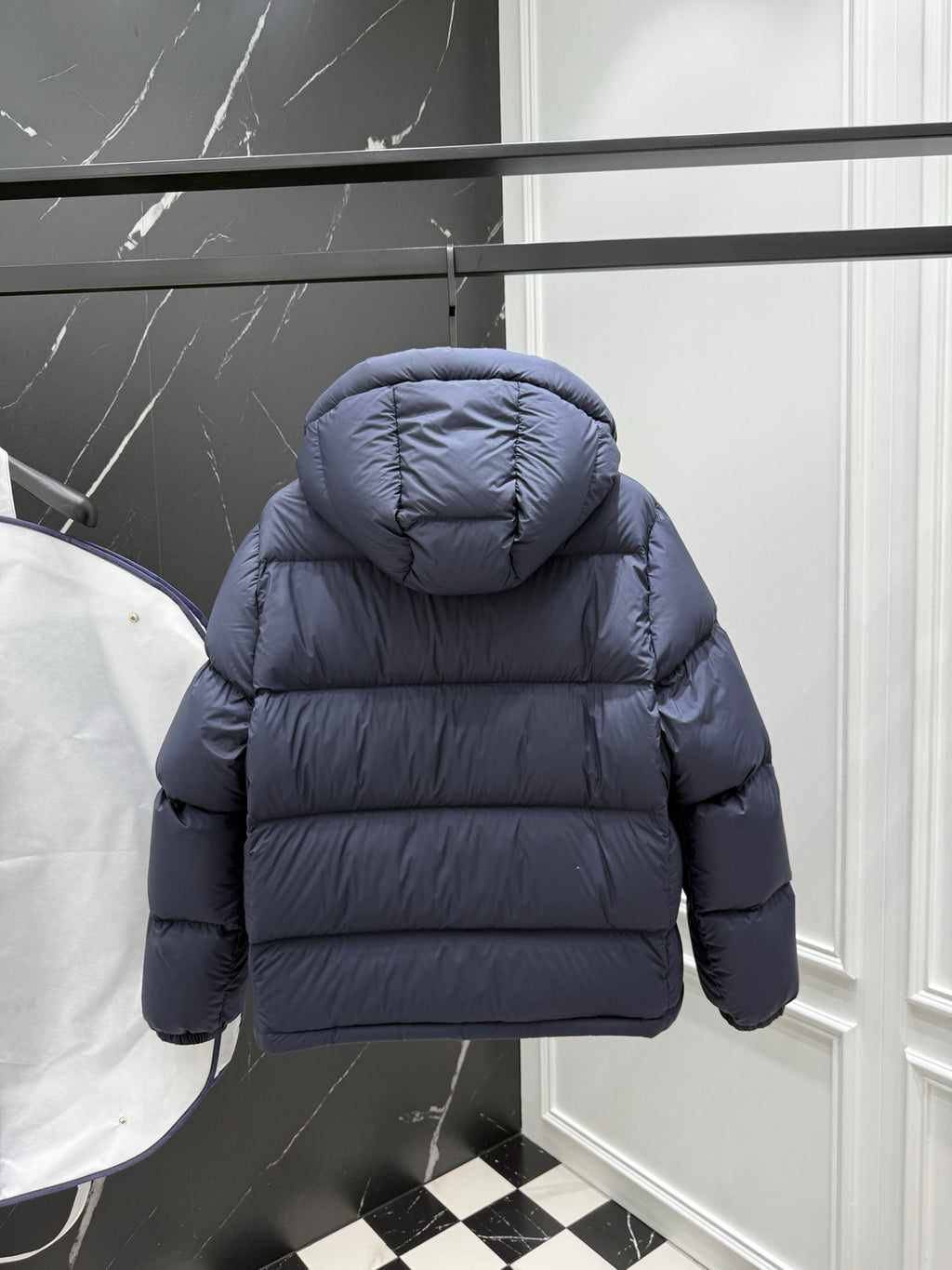 Dark blue puffer jacket with hood, rear view, and rounded shoulders