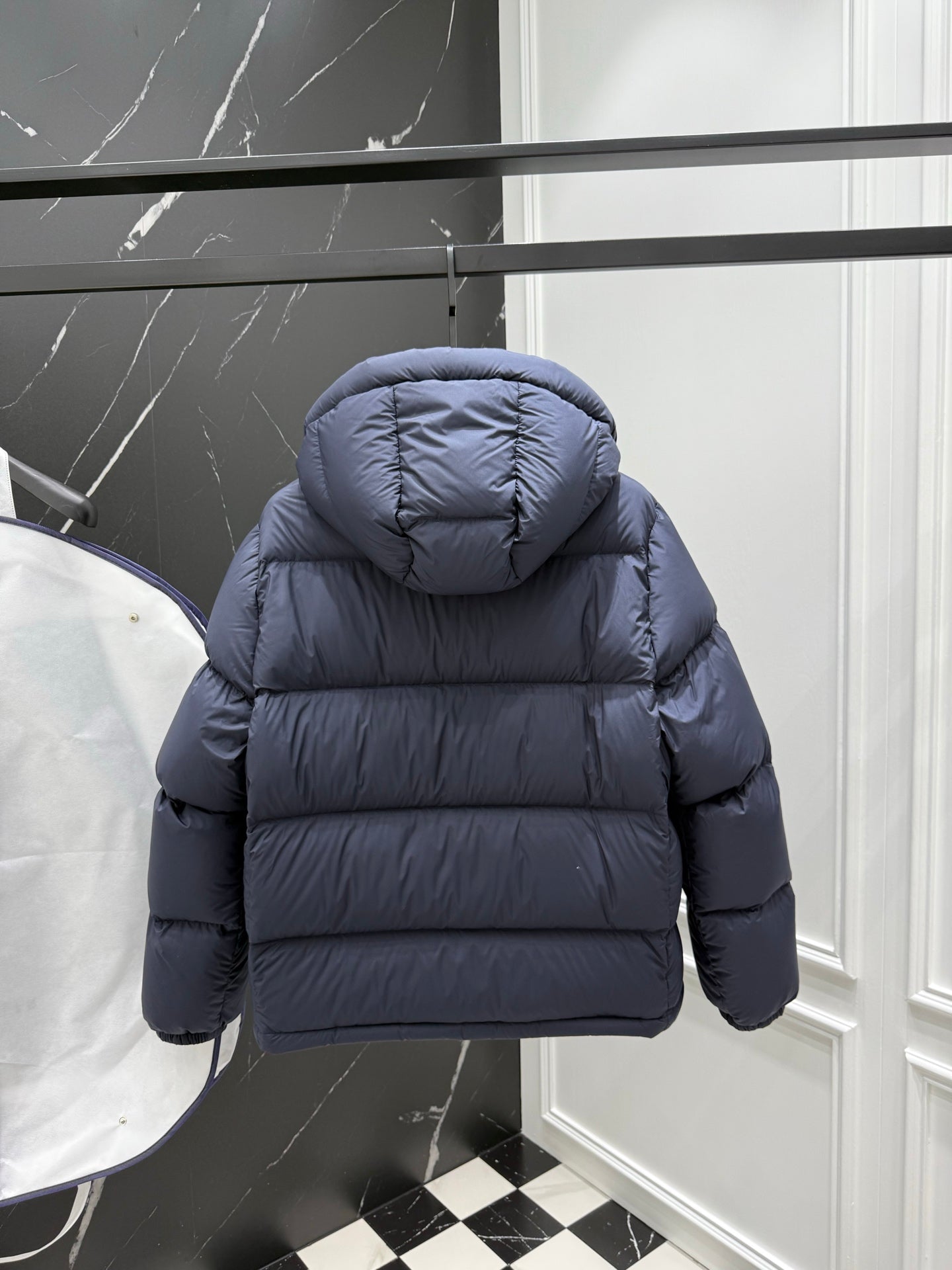 Dark blue puffer jacket with hood, rear view, and rounded shoulders