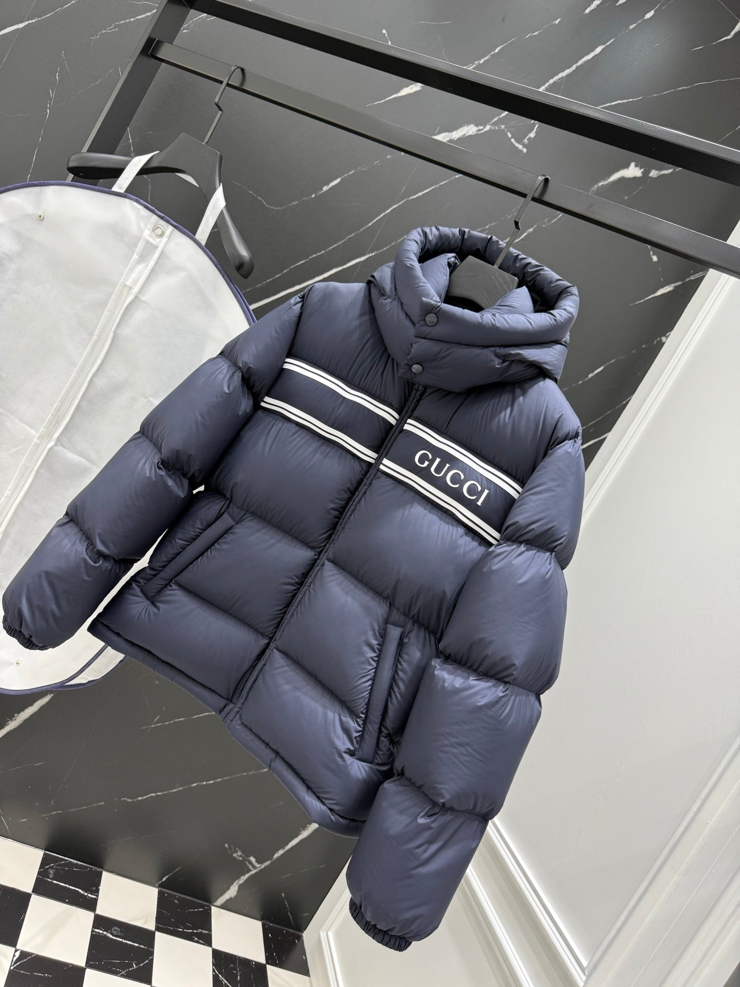 Dark blue puffer jacket with hood and Gucci logo band across chest