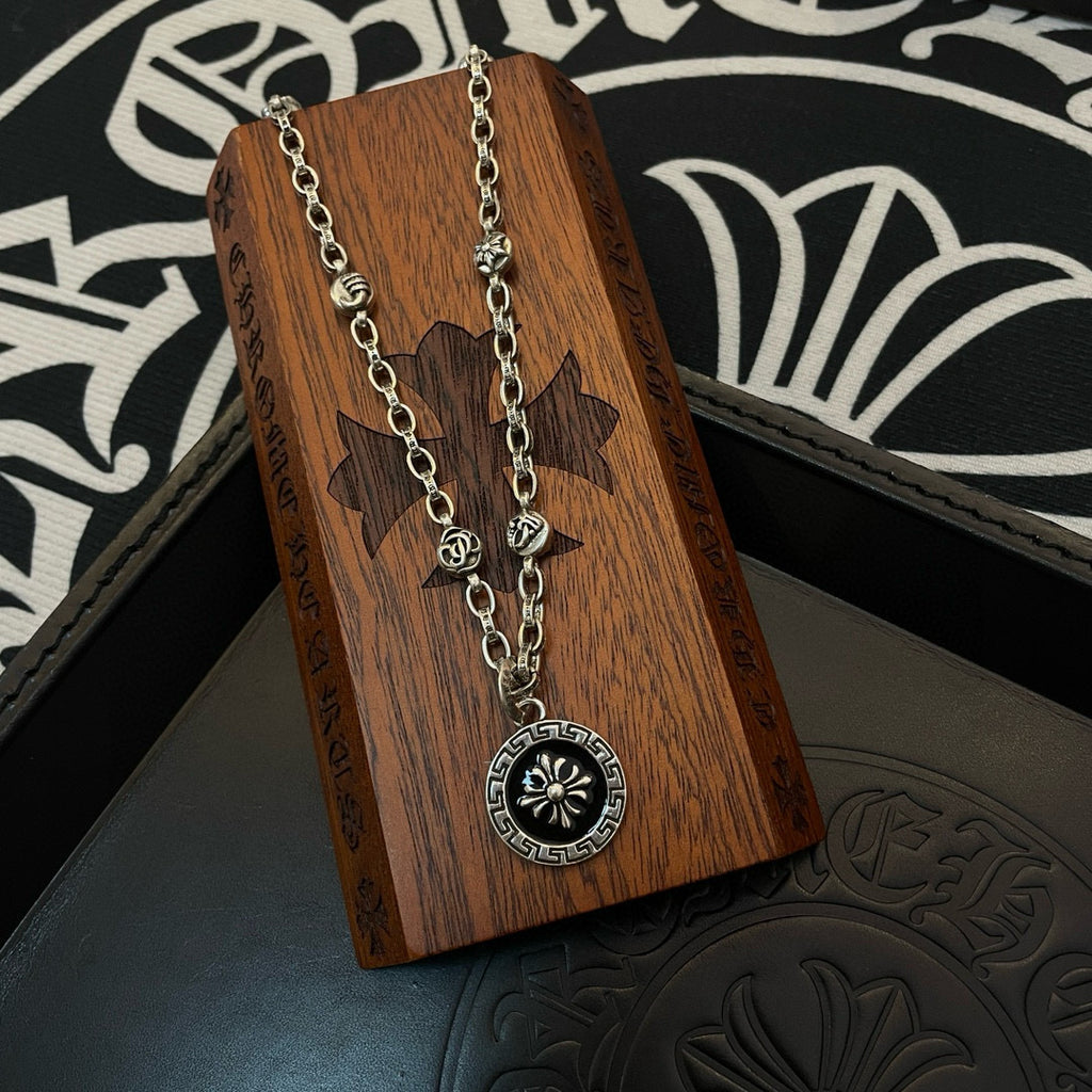 Silver-tone round pendant necklace with sunburst medallion on a wooden display