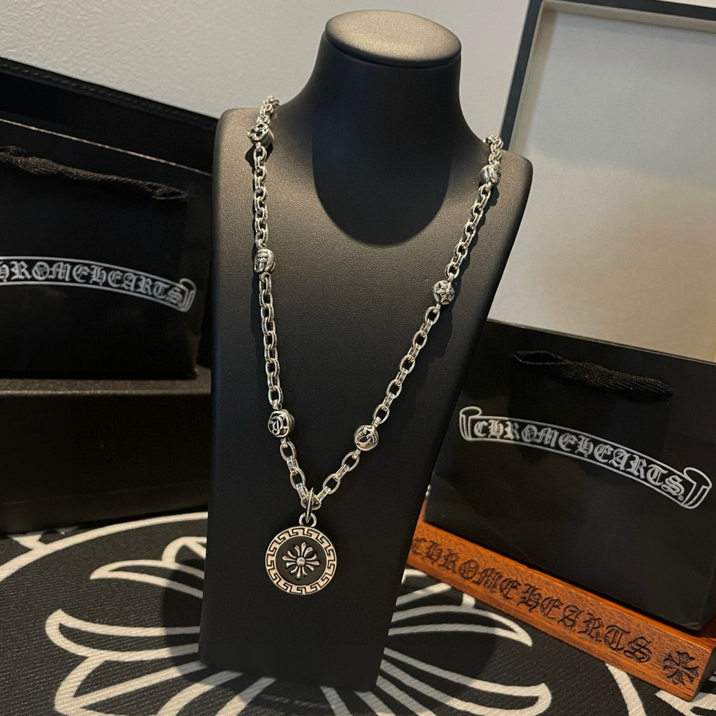 Silver-tone pendant necklace featuring a round sunburst medallion on a linked chain