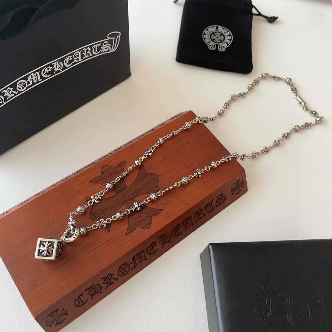 Silver-tone charm necklace with square flower pendant and layered chain styling