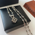 Silver-tone charm necklace with square flower pendant and dangling bead details