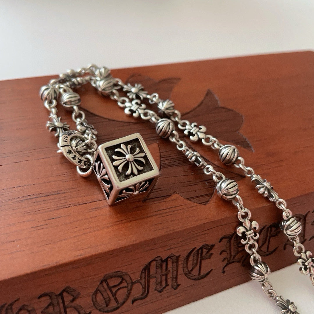 Silver-tone charm necklace with square flower pendant and oval bead spacers