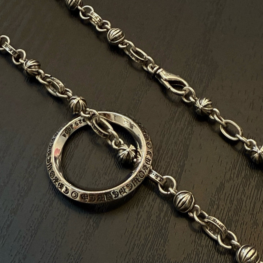 Silver ring pendant necklace with decorative link chain, close-up on ring charm.