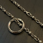 Silver ring pendant necklace with decorative link chain, close-up on ring charm.