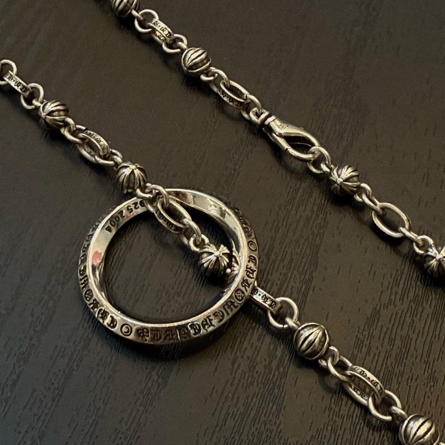 Silver ring pendant necklace with decorative link chain, close-up on ring charm.
