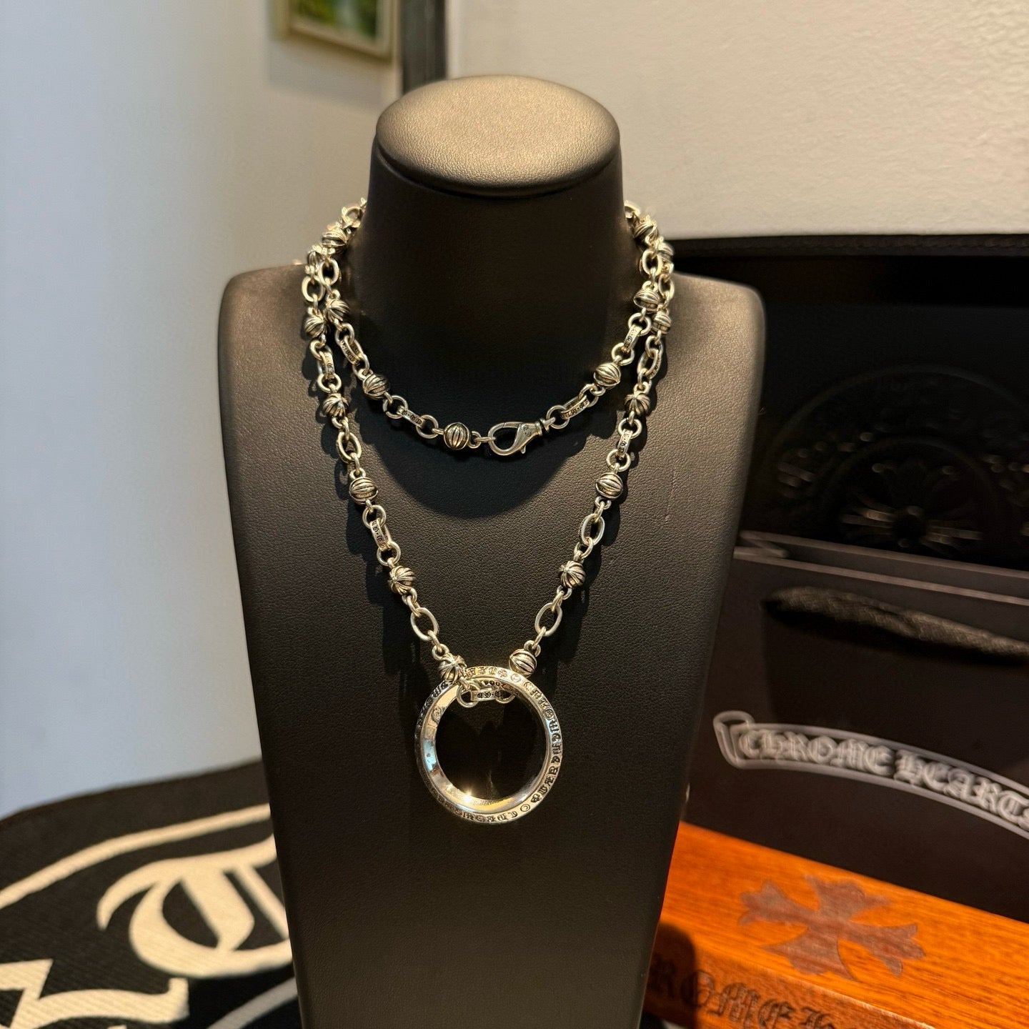 Silver chain necklace with circular ring pendant and long layered links on bust.