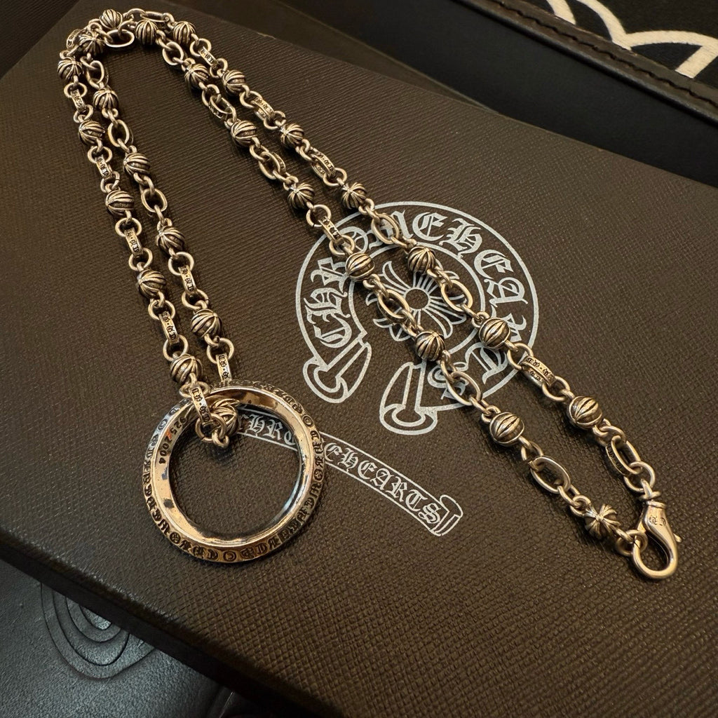 Silver charm necklace with circular ring pendant and long chain strand on box.
